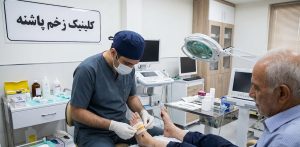 پزشک متخصص در حال انجام مراحل مراقبتی و پانسمان تخصصی بیمار سالمند به عنوان بخشی از پروسه درمان قطعی زخم پای دیابتی در کلینیک پاشنه.