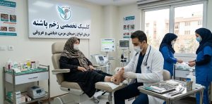 پزشک متخصص در حال انجام مراحل درمان تخصصی انواع زخم بر روی پای یک بیمار مسن در کلینیک زخم پاشنه، با استفاده از تجهیزات پیشرفته و در حضور پرستاران.