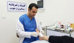 پزشک متخصص در حال انجام پانسمان استریل برای پیشگیری از عفونت زخم پا در کلینیک زخم پاشنه تهران.