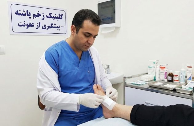 پزشک متخصص در حال انجام پانسمان استریل برای پیشگیری از عفونت زخم پا در کلینیک زخم پاشنه تهران.