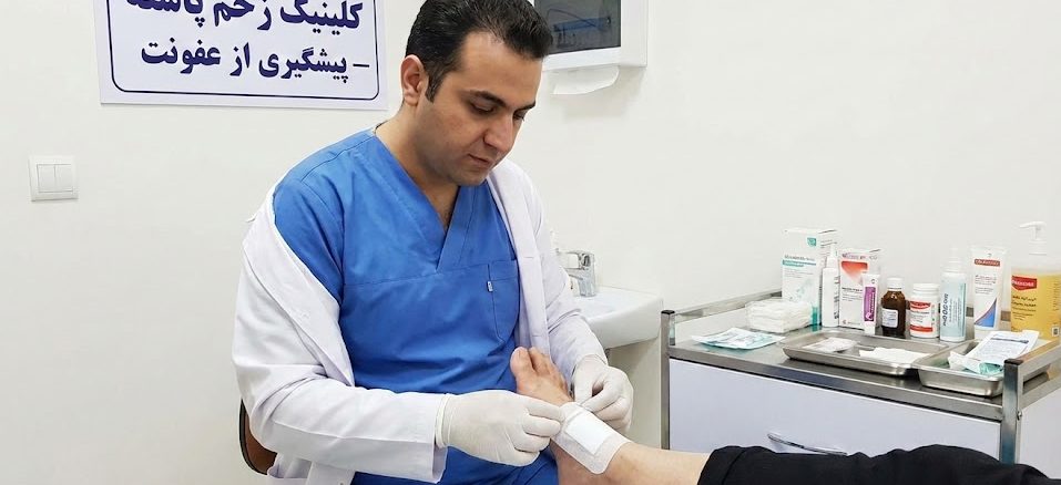 پزشک متخصص در حال انجام پانسمان استریل برای پیشگیری از عفونت زخم پا در کلینیک زخم پاشنه تهران.
