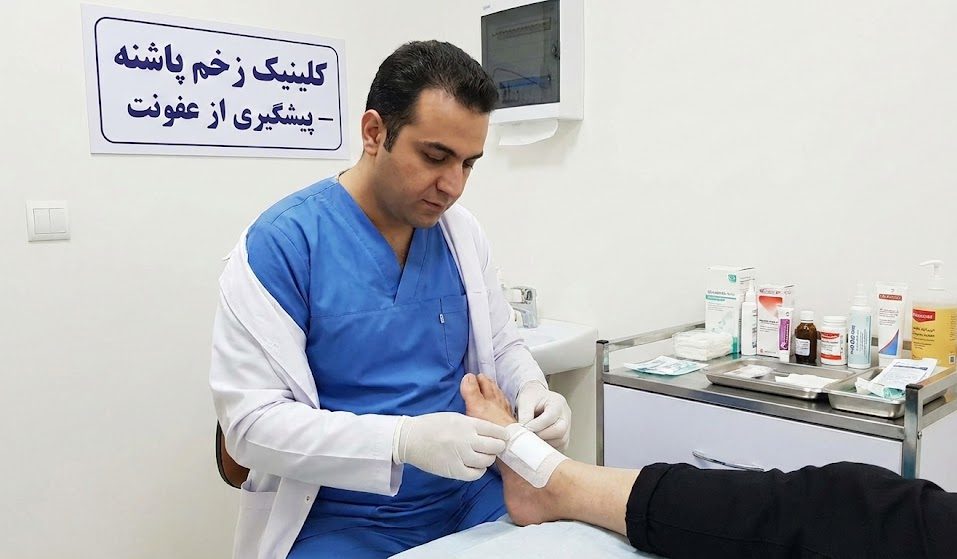 پزشک متخصص در حال انجام پانسمان استریل برای پیشگیری از عفونت زخم پا در کلینیک زخم پاشنه تهران.