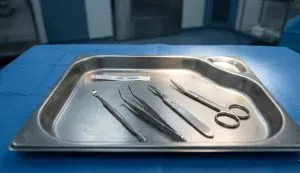 سینی استیل حاوی ست کامل و استریل ابزارهای جراحی شامل تیغ، پنس و کورت که برای جراحی سرپایی زخم در تهران آماده شده است.