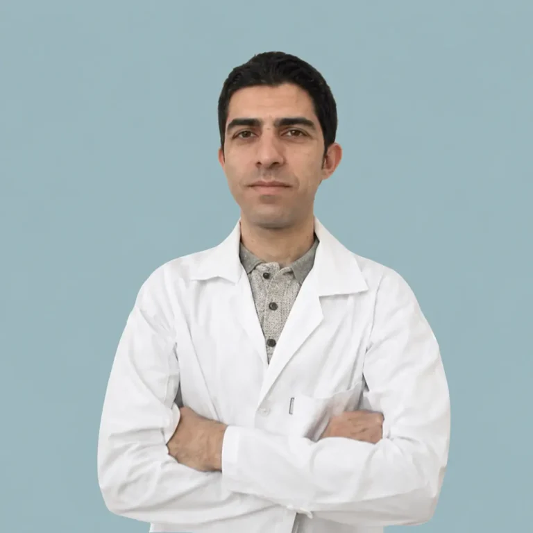 پرتره رسمی دکتر سید حسین ملک پور، دکتری علوم آزمایشگاهی و متخصص تشخیص عفونت با کت آزمایشگاهی سفید، دست‌های ضربدری و گردنبند نقره، در برابر پس‌زمینه آبی-خاکستری.
